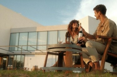Young couple sharing a bottle of wine during sunset outside Finca de los Arandinos hotel, Entrena, Spain.