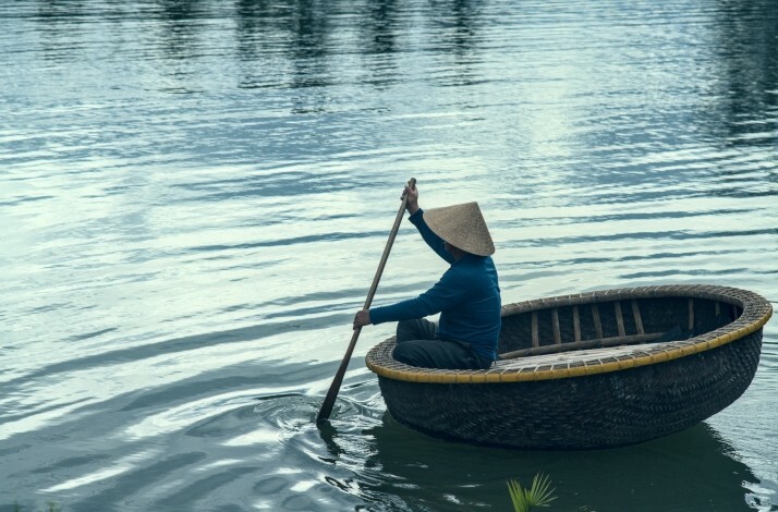 Traditional basket boat with a person rowing on calm water