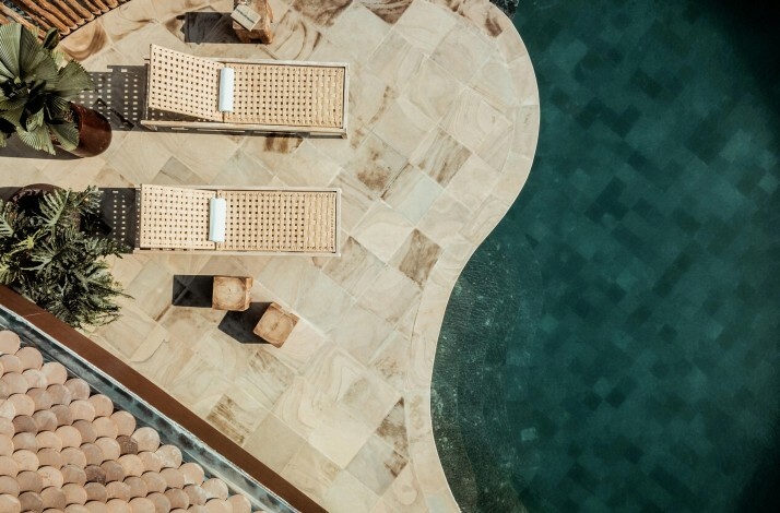 Top-down view of sun loungers, plants, and swimming pool corner