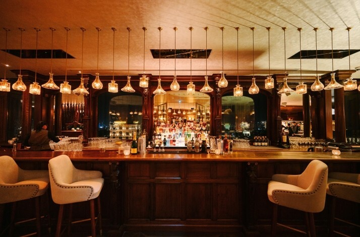 Albion Saigon restaurant's dimly lit bar area with ornate wooden fixtures and hanging glass pendant lights.