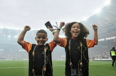 Children in honorary captain uniforms posing on a soccer field