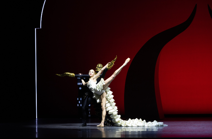 Duet with dancer in white, dramatic pose, gold gloves, bold red and black set.