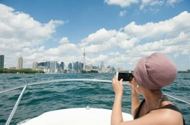 A girl takes a photo of Toronto from the Harbour Cruise.