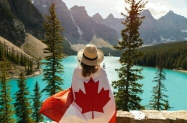 Girl in a hat and with a Canadian flag on her shoulders against the backdrop of Moraine Lake.