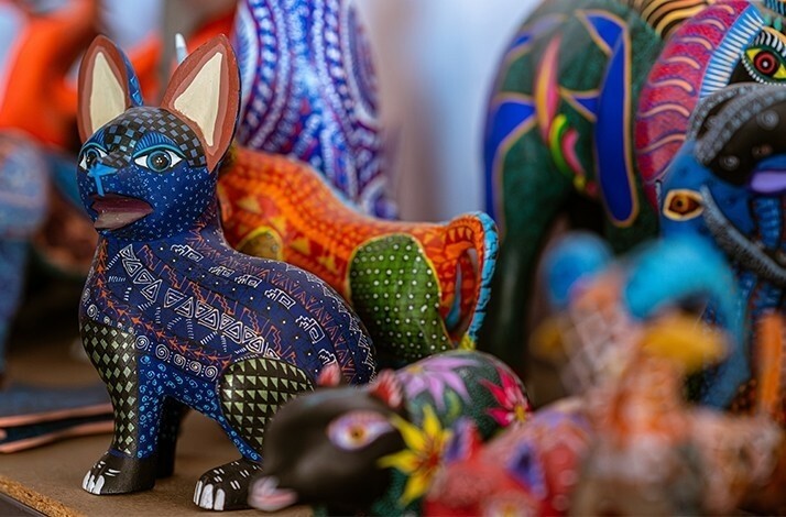 A display of several colorful, hand-painted animal figurines, with a blue and white patterned creature in the foreground.