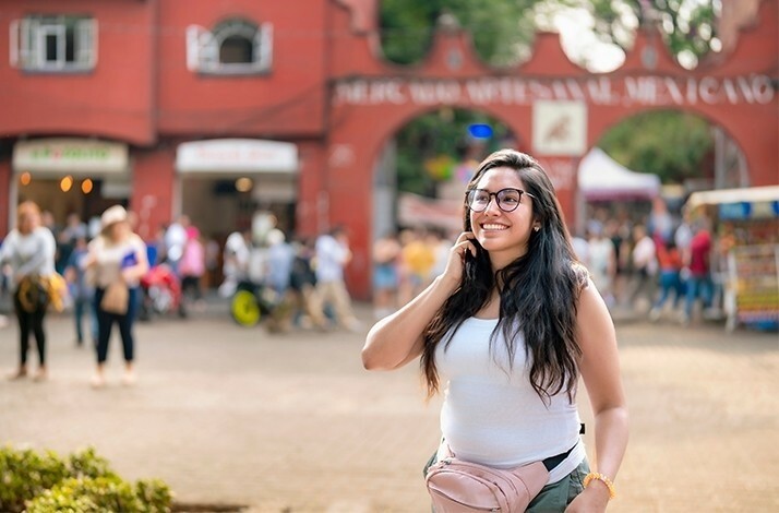 A girl smiling brightly while standing on a colorful street in Mexico.