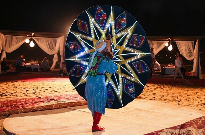 Performer showcasing a LED-lit tanoura dance at a desert camp.