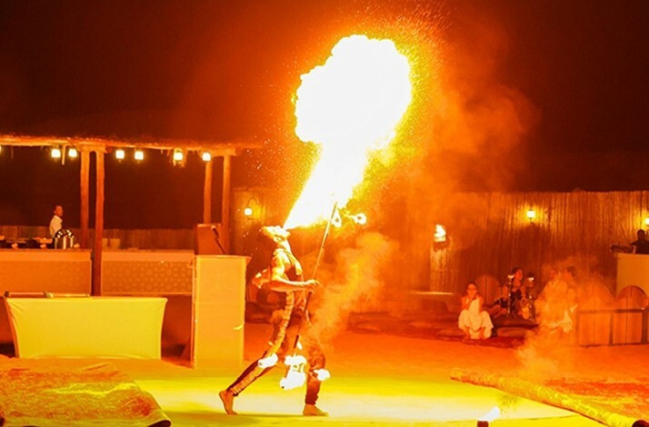 Performer doing a fire-breathing act at a desert camp.