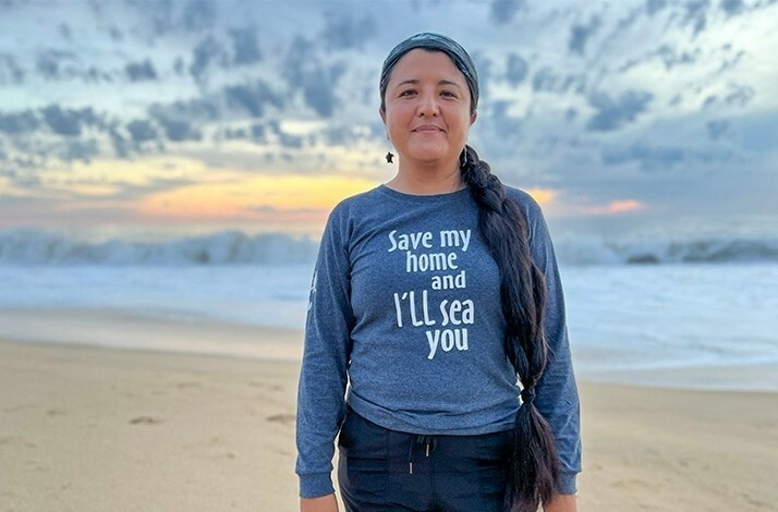 A woman posing for the photo on the shore during sunset