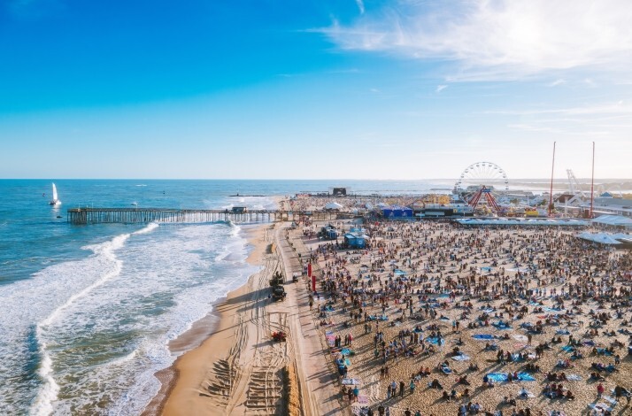 A large crowd gathered in a beach on a sunny day at Country Calling Music Festival.