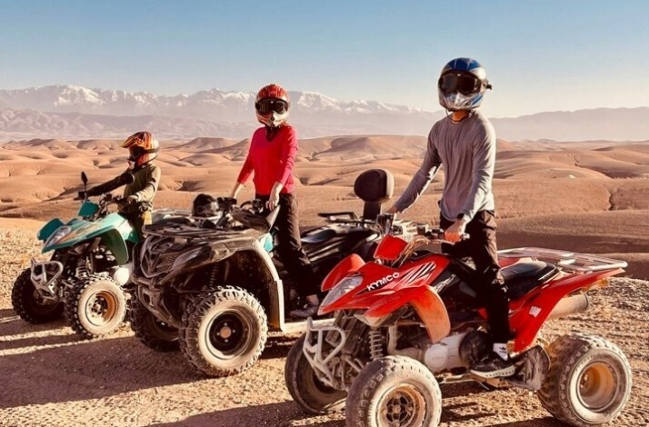 Three people riding quad bikes across rocky trails.