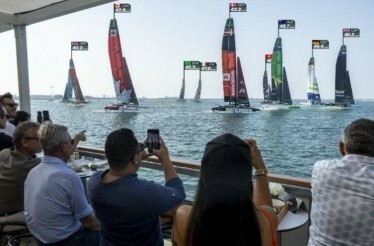 Guests enjoy front-row waterfront seating, watching SailGP yachts race by and capturing the action on their phones.