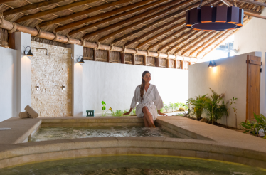 A woman in a white robe sits at the edge of a spa tub, at Hotel El Ganzo