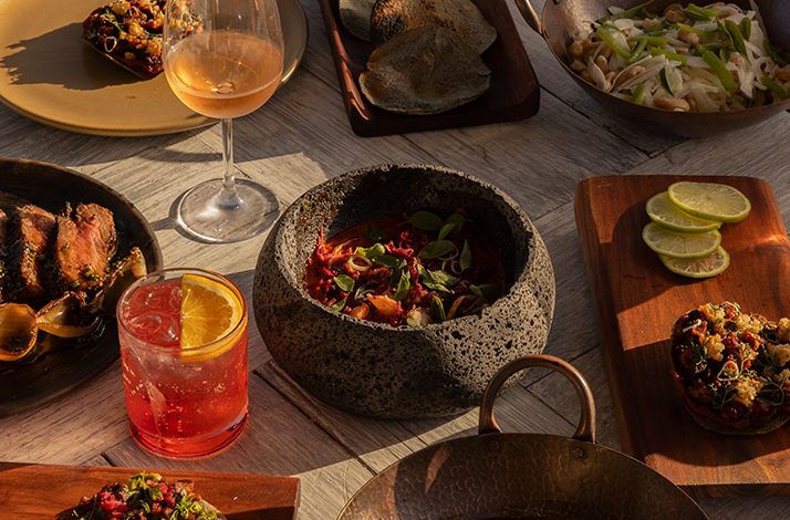 Arrangement of various dishes and beverages on a rustic wooden table at Hotel El Ganzo