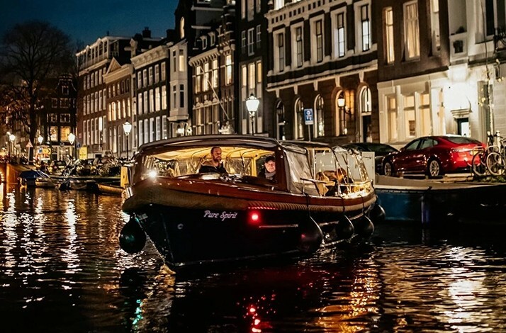 Front view of the elegant Pure Spirit on the shimmering canals of Amsterdam during the Light Festival.