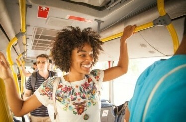 Passengers standing and holding yellow handrails inside a Ticketpro Bus in South Africa.