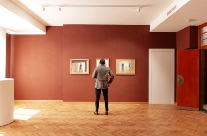 Person viewing paintings in an art gallery.