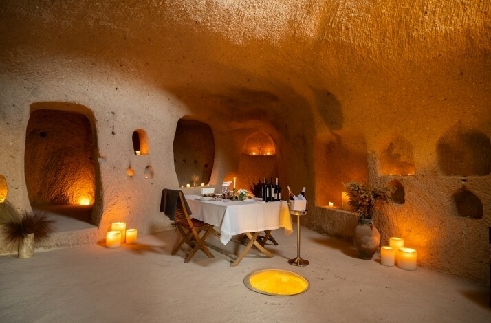 An authentic cave room lit by the candlelight with a table served for two at Taskonaklar Hotel Cappadocia.