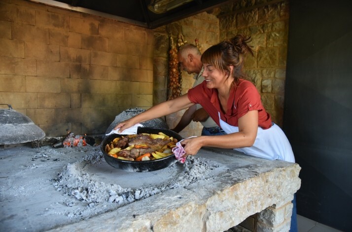 Person cooking peka, a traditional Dalmatian dish, during a private cooking workshop