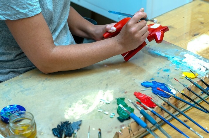 A person carefully painting a Dala horse in Sweden's oldest Dala horse-making workshop