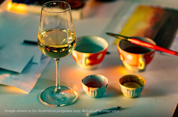 A glass of white wine sits on a table alongside small colorful bowls, a paintbrush, and art supplies, with warm lighting and a note stating the image is for illustrative purposes only.