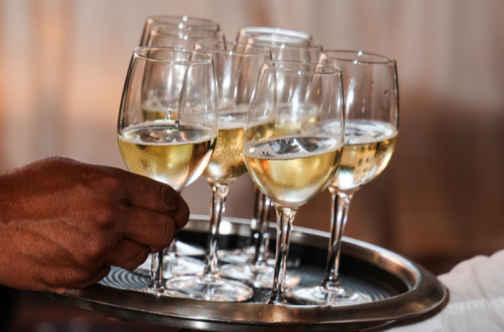 A tray with multiple glasses of white wine being served.