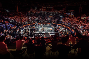 The interior of Rajadamnern Stadium filled with spectators on a Thai boxing match, as viewed from the VIP lounge.