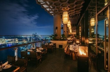 An open-air terrace of Mott 32 Dubai restaurant overlooking nighttime Dubai.