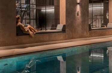 A person sitting next to a swimming pool at the  The Edwardian Hotel Manchester spa.