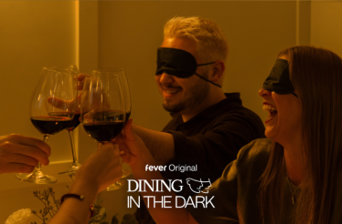 Two blindfolded people cheering with wine glasses. Text at the bottom: 'fever Original. Dining in the Dark'.