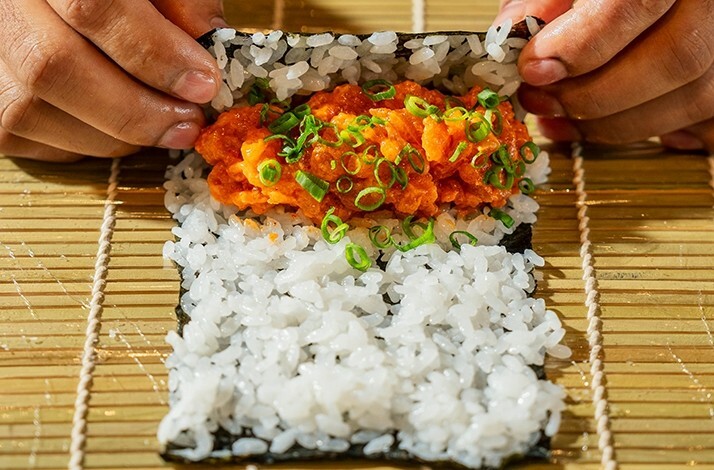 Fresh sushi being hand‑rolled, reflecting the finely crafted dishes featured in the Goldfish Bites experience.