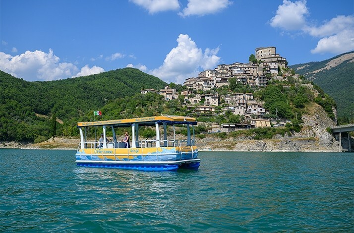 A boat in Lake Turano with a picturesque view at the hill where village Castel di Tora is situated.