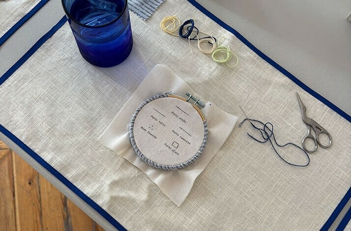 Embroidery hoop, threads, scissors, and a glass set up for stitching practice.