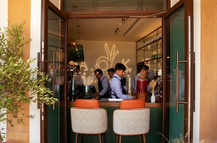 An open doorway looks into interior of A.O.K. Kitchen, where staff work behind a counter.