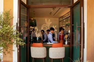 An open doorway looks into interior of A.O.K. Kitchen, where staff work behind a counter.