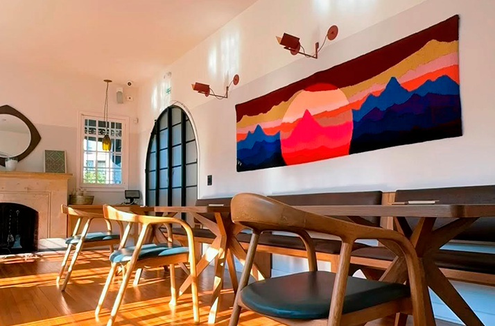 Interior of the restaurant showcasing modern design elements and artisan details, including a colorful wall tapestry that adds warmth to the space