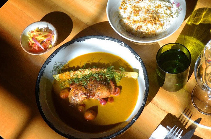 A beautifully plated dish featuring protein, vegetables, and side accompaniments, presented under natural light that enhances its colors