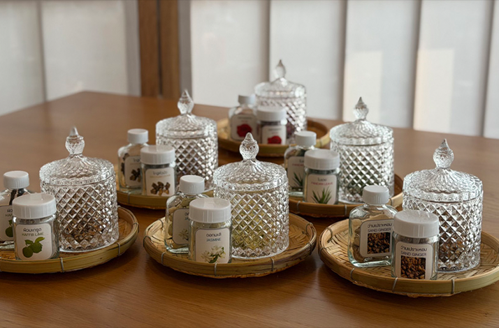 Trays of traditional Thai herbs and crystal jars arranged for a wellness workshop.