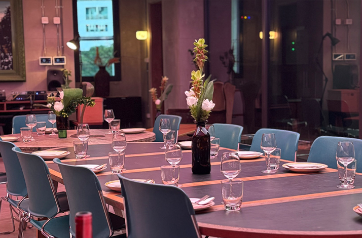  A dining table set with plates, glasses, and floral arrangements in a modern space.