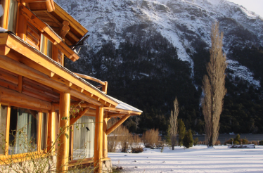 Wooden eco‑lodge framed by snow‑dusted mountains, reflecting stillness and connection with nature.