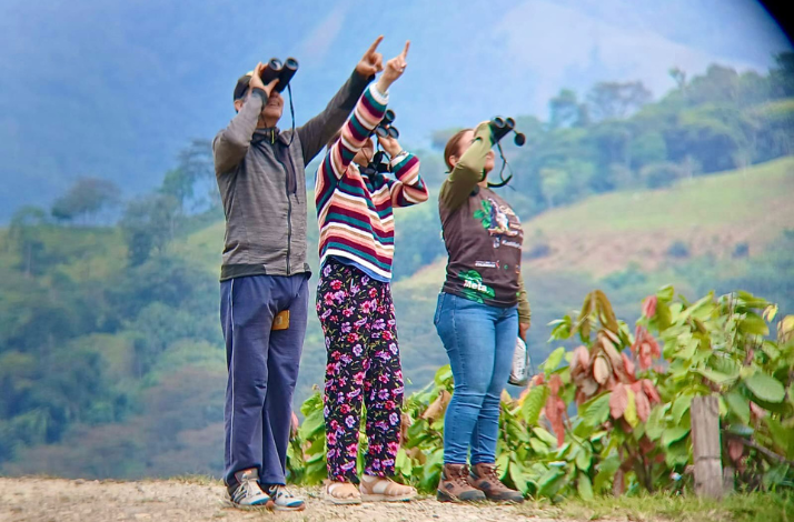 Three people pointing at a abird they watched