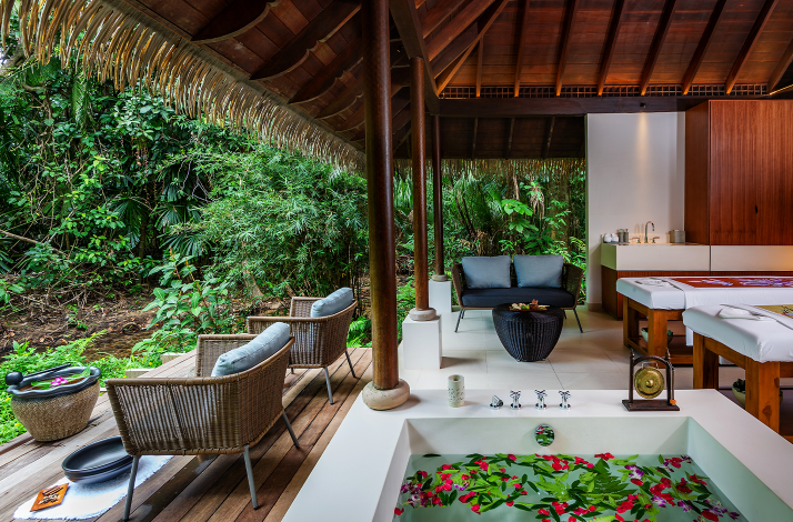 Luxury open-air spa villa at The Datai Langkawi featuring a floral bath and massage beds facing a lush rainforest.