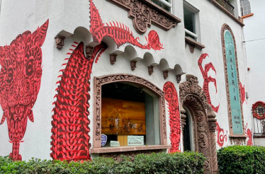 Exterior view of Galería Oscar Román featuring striking red contemporary murals on the façade.