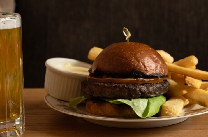 Hamburger paired with fried potatoes and a glass of beer served at Trudie's Tavern.