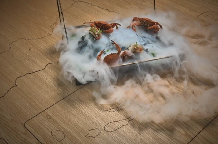 Artistic seafood dish with crabs presented on a tray surrounded by dramatic clouds of vapor, served at Michelin-starred LAB by Sergi Arola.