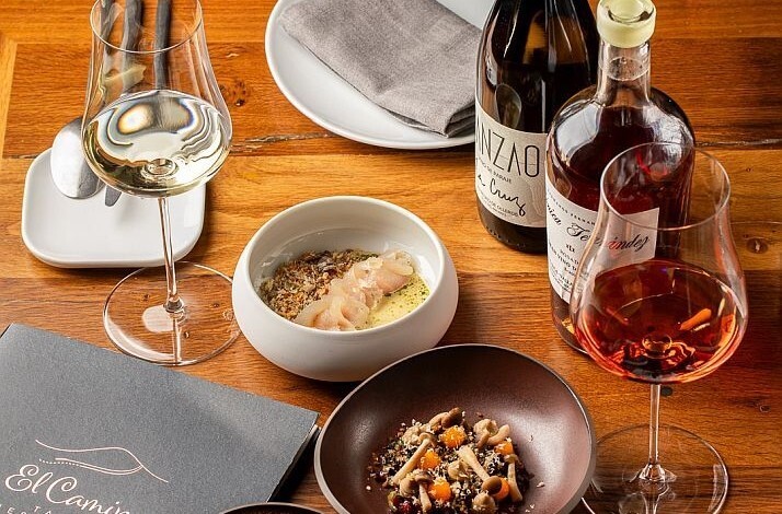 A gourmet meal with wine and artisanal dishes served on a wooden table at El Camino Tapas Restaurant.