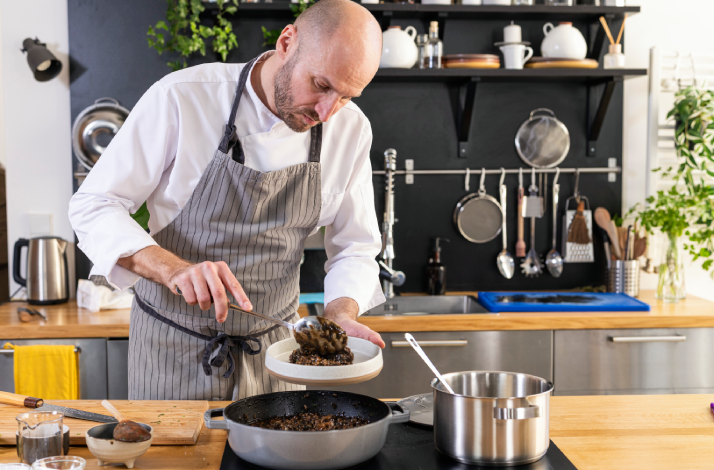 Chef puts a portion of Dalmatian black risotto on a plate.