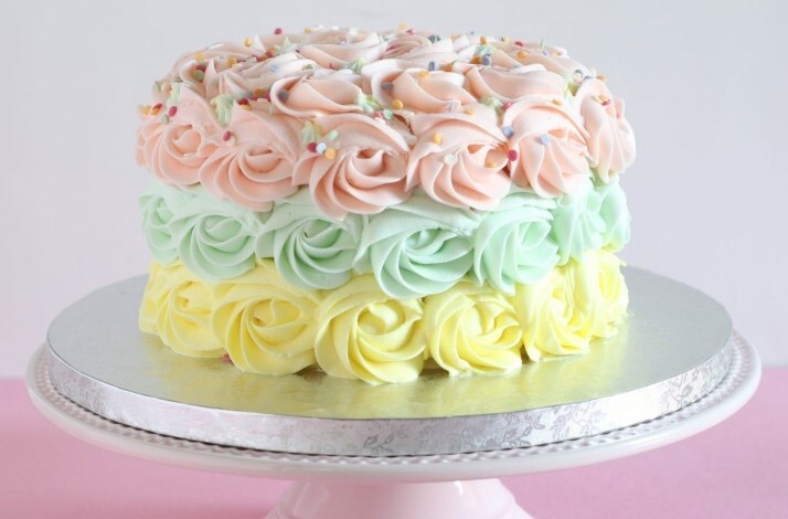 Cake with 3 layers of piping in yellow, green and pink buttercream frosting and sprinkled with edible elements