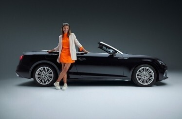The lady leaning on a black convertible car, as part of a promotional campaign for a rental service SIXT.
