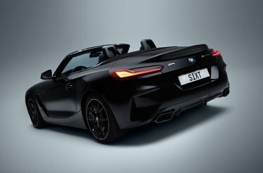 Black BMW Z4 convertible with top down, shown from rear three-quarter angle, bearing 'S1XT' licence plate for SIXT car rental.
